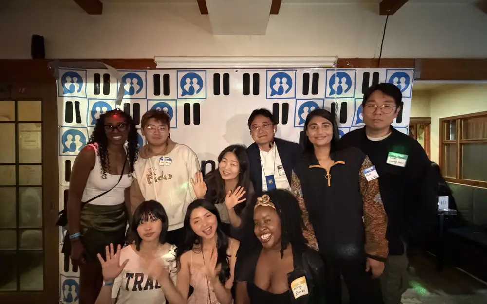 A group of new friends waving in front of the nurio backdrop