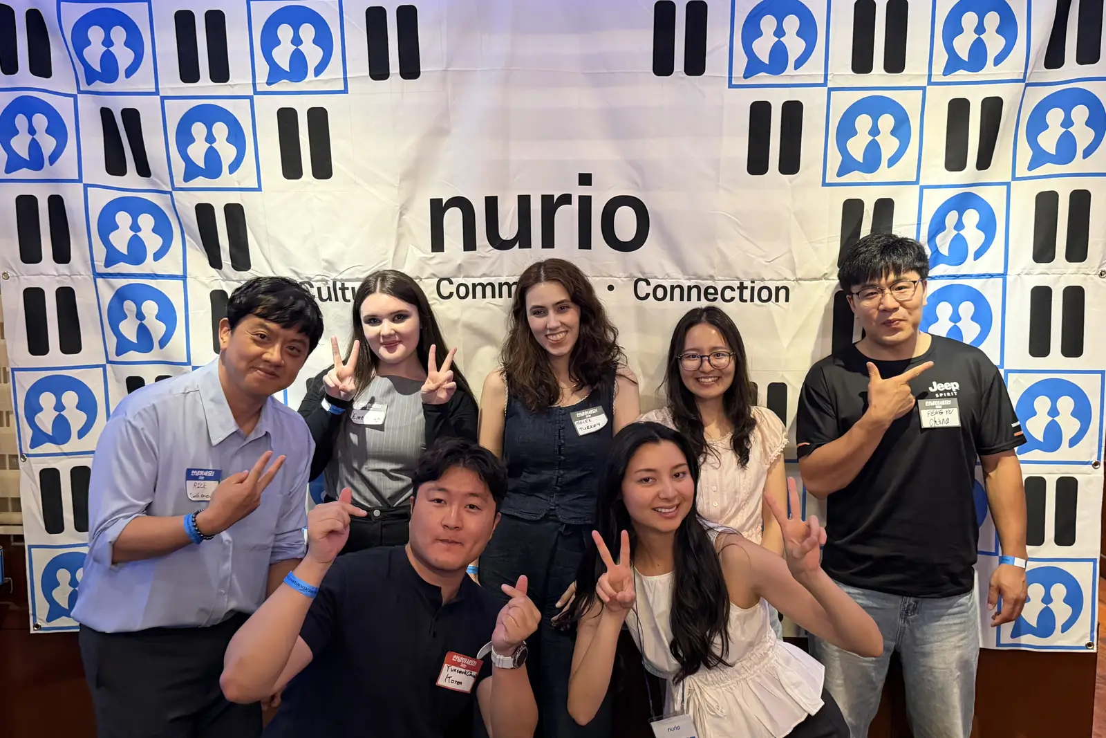 Guests of a nurio international party posing together in front of the nurio backdrop
